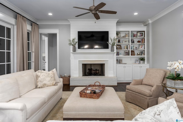 living room with crown molding, a fireplace, ceiling fan, and light hardwood / wood-style flooring