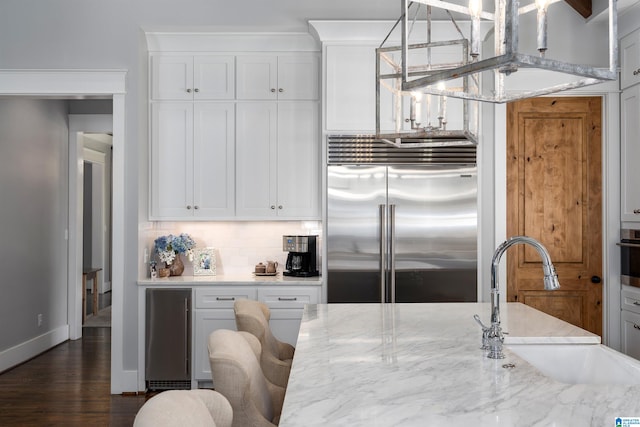 kitchen featuring light stone countertops, white cabinets, decorative light fixtures, and appliances with stainless steel finishes