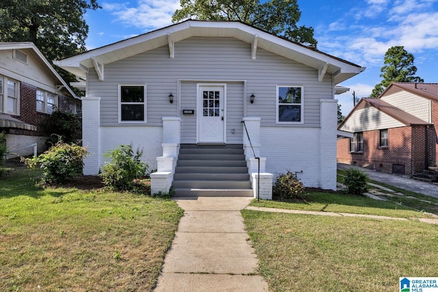 bungalow-style home with a front yard and brick siding