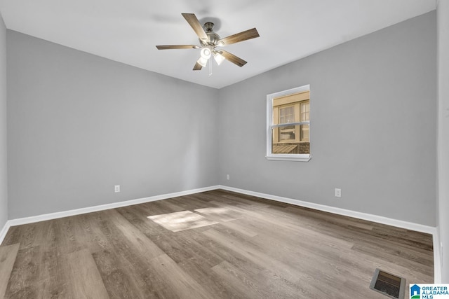 spare room featuring a ceiling fan, visible vents, wood finished floors, and baseboards