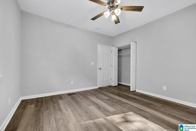unfurnished bedroom with a closet, ceiling fan, visible vents, baseboards, and wood finished floors