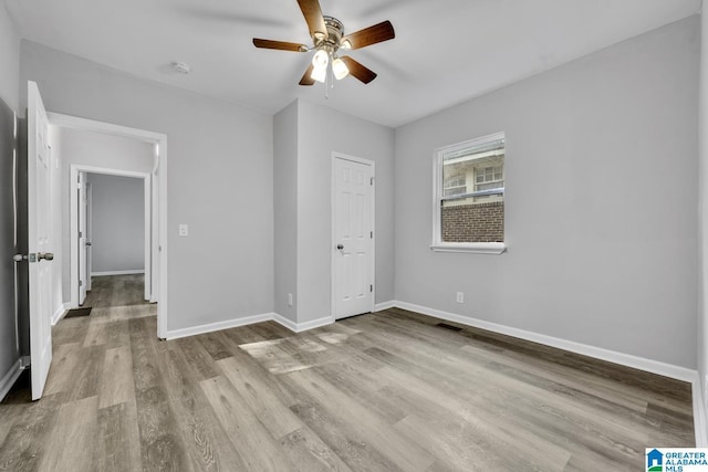 unfurnished bedroom with baseboards, visible vents, wood finished floors, and ceiling fan
