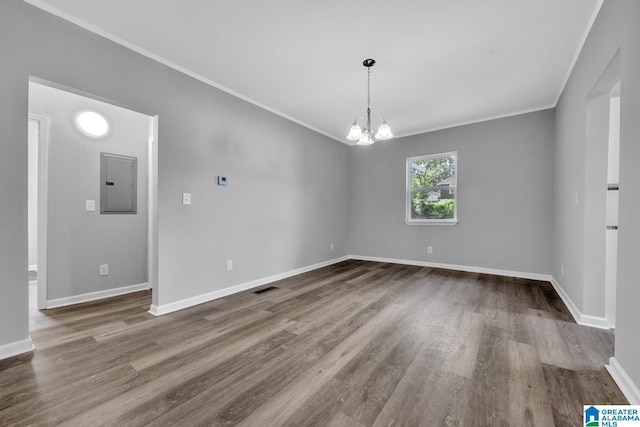 spare room featuring electric panel, a chandelier, wood finished floors, and visible vents