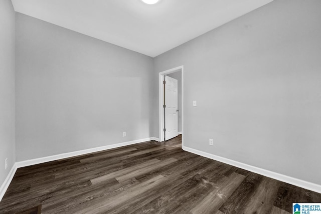 empty room featuring dark wood-style floors, vaulted ceiling, and baseboards