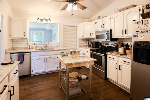 kitchen featuring white cabinets, stainless steel appliances, sink, and vaulted ceiling