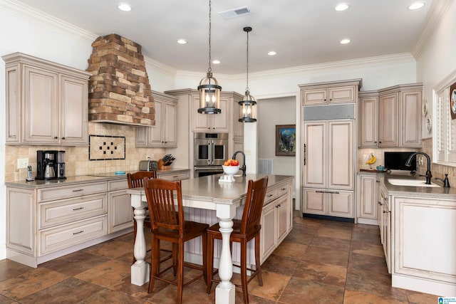 kitchen with paneled built in refrigerator, a center island with sink, sink, hanging light fixtures, and double oven