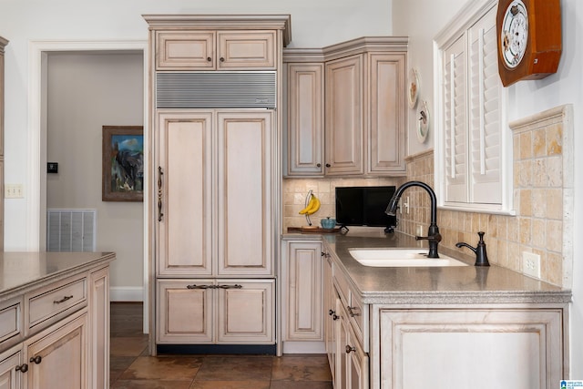 kitchen with light brown cabinetry, dark tile patterned flooring, sink, and tasteful backsplash