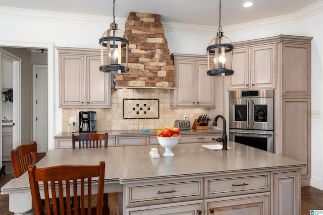 kitchen with crown molding, stainless steel double oven, a center island with sink, decorative light fixtures, and sink