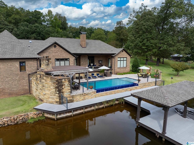 view of pool featuring a water view, a patio, and a lawn