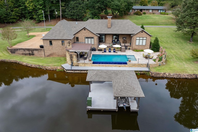 rear view of house featuring a water view, a patio, and a lawn