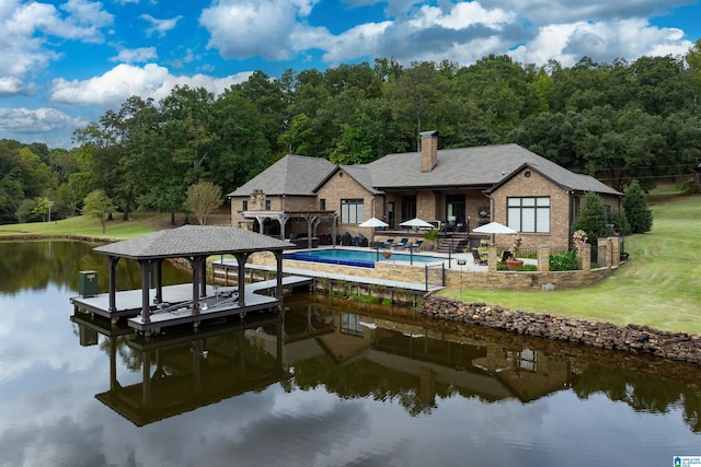 back of property featuring a water view, a patio, and a lawn