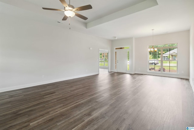 unfurnished living room with ceiling fan with notable chandelier, dark wood-type flooring, and a wealth of natural light