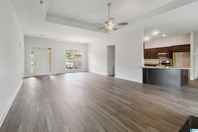 unfurnished living room with ceiling fan with notable chandelier, sink, and dark hardwood / wood-style flooring