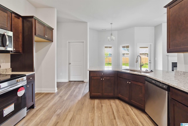 kitchen featuring stainless steel appliances, a notable chandelier, sink, and light wood-type flooring