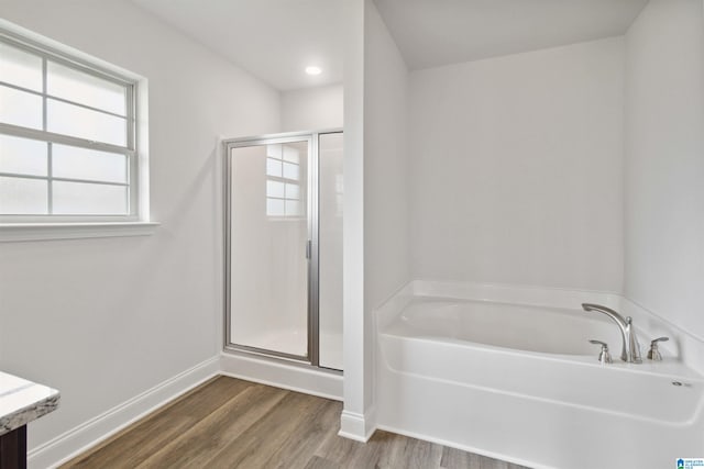 bathroom featuring plus walk in shower and hardwood / wood-style flooring