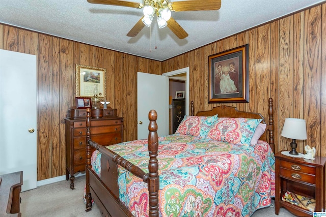 carpeted bedroom with ceiling fan, a textured ceiling, and wooden walls