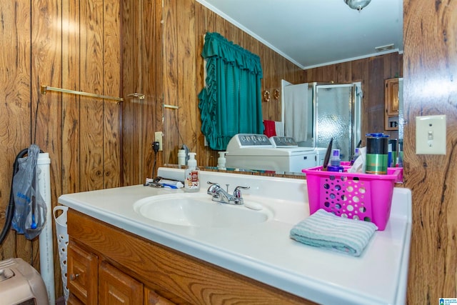 bathroom with vanity, wooden walls, washing machine and dryer, walk in shower, and crown molding