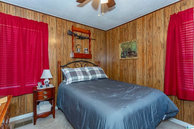 carpeted bedroom featuring wood walls, a textured ceiling, and ceiling fan