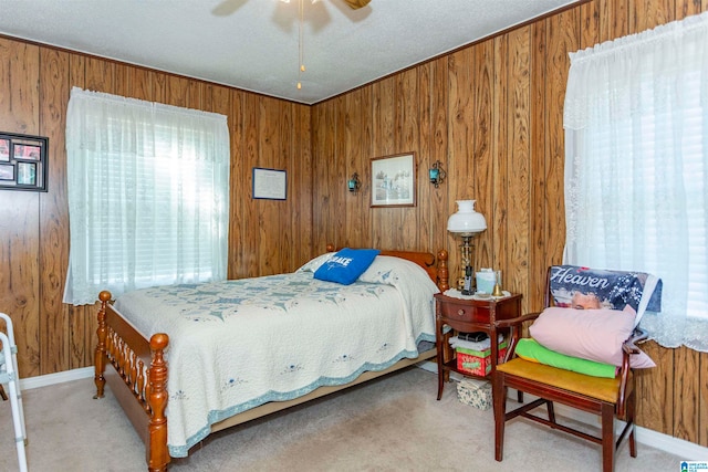 carpeted bedroom with ceiling fan and wood walls