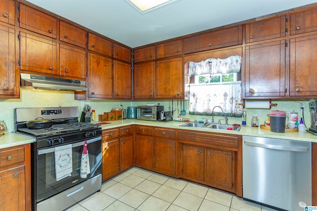 kitchen with appliances with stainless steel finishes, sink, and light tile patterned flooring