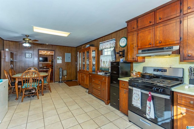 kitchen featuring ceiling fan, gas stove, wood walls, and light tile patterned flooring