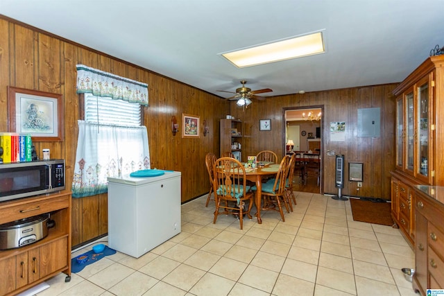 tiled dining room featuring ceiling fan, electric panel, and wood walls