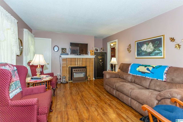 living room with a brick fireplace and hardwood / wood-style floors