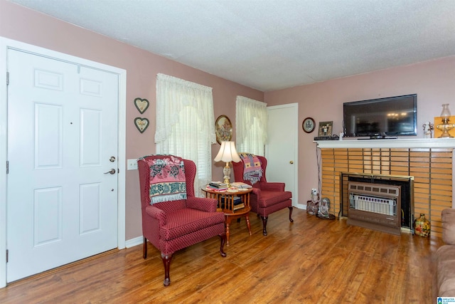 sitting room with a fireplace, wood-type flooring, and a textured ceiling