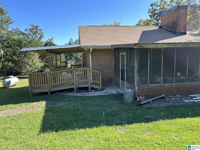 rear view of house featuring a sunroom, a lawn, and a wooden deck