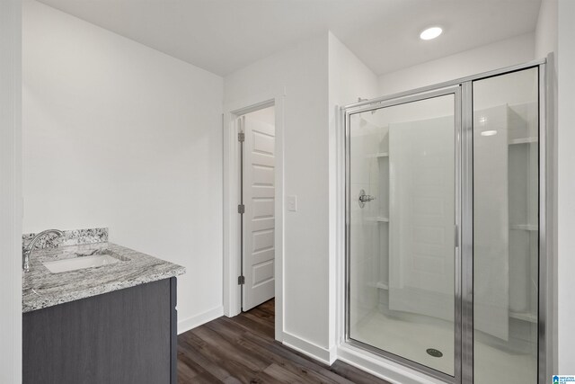 bathroom with walk in shower, vanity, and hardwood / wood-style flooring