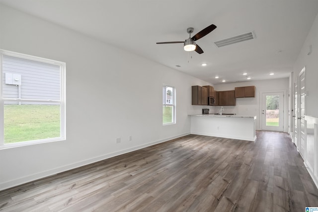 unfurnished living room featuring ceiling fan, hardwood / wood-style flooring, a wealth of natural light, and sink