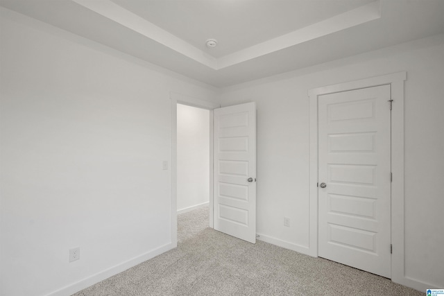 unfurnished bedroom featuring a tray ceiling and light carpet