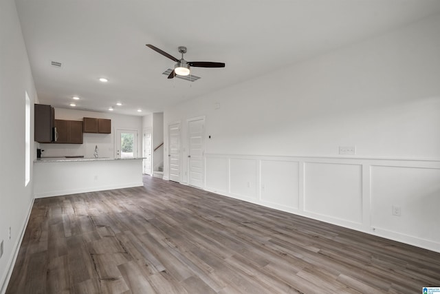 unfurnished living room featuring dark hardwood / wood-style floors, sink, and ceiling fan