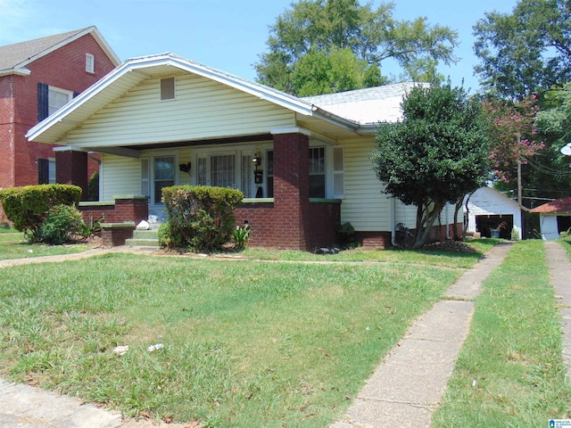 2820 20th St, Ensley, Birmingham, AL 35208 - view of front of house featuring covered porch, a front yard, a detached garage, an outdoor structure, and brick siding
