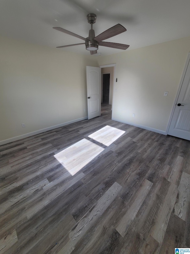 unfurnished room with ceiling fan and dark wood-type flooring