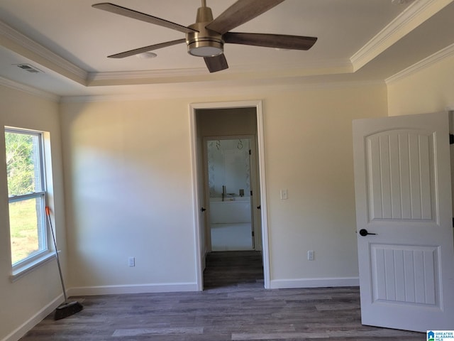 unfurnished bedroom featuring ceiling fan, dark wood-type flooring, ornamental molding, and a raised ceiling