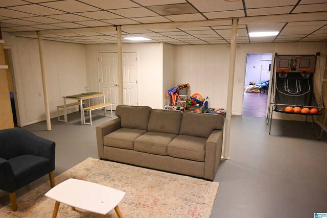 living room featuring a paneled ceiling and concrete floors