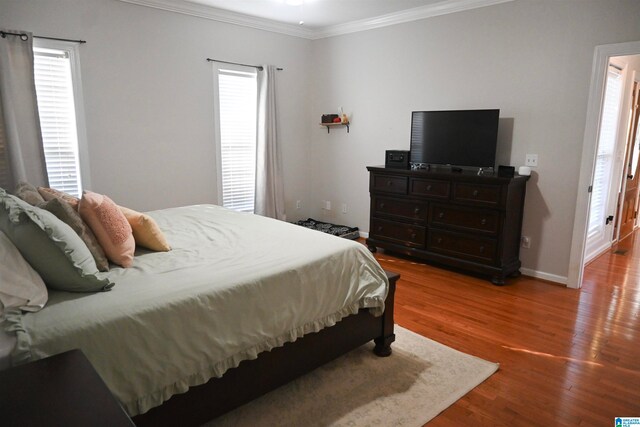 bedroom with multiple windows, crown molding, and hardwood / wood-style floors