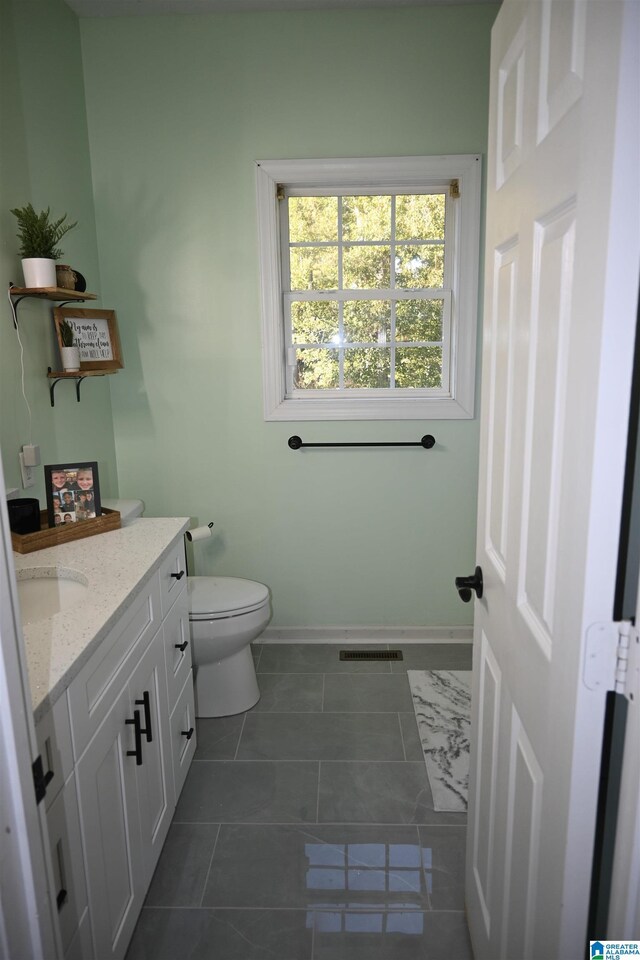 bathroom with visible vents, baseboards, toilet, vanity, and tile patterned flooring
