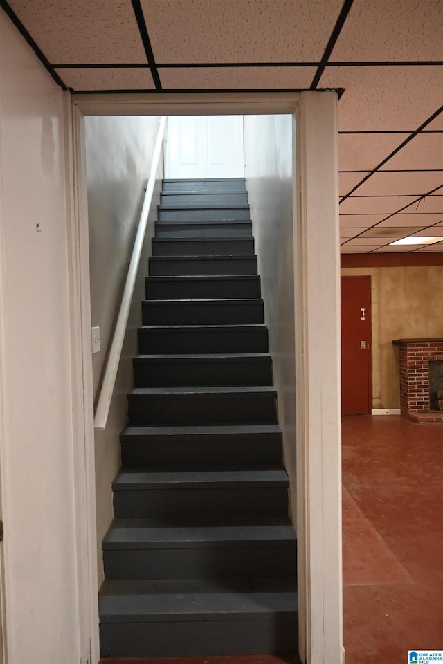 stairs with a paneled ceiling and a fireplace