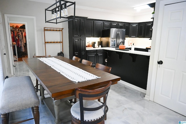 interior space with crown molding, an inviting chandelier, stainless steel fridge with ice dispenser, decorative light fixtures, and a kitchen breakfast bar