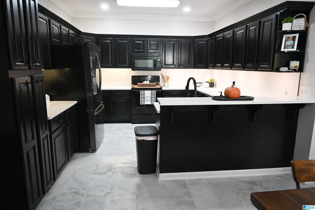 kitchen featuring kitchen peninsula, crown molding, black appliances, and a breakfast bar