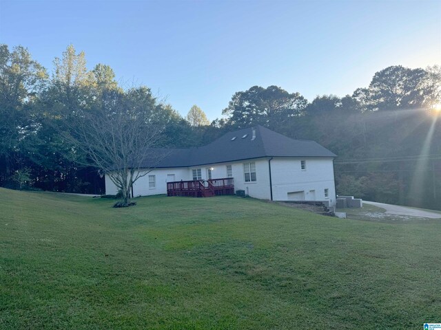 rear view of house with a garage, a lawn, and a deck