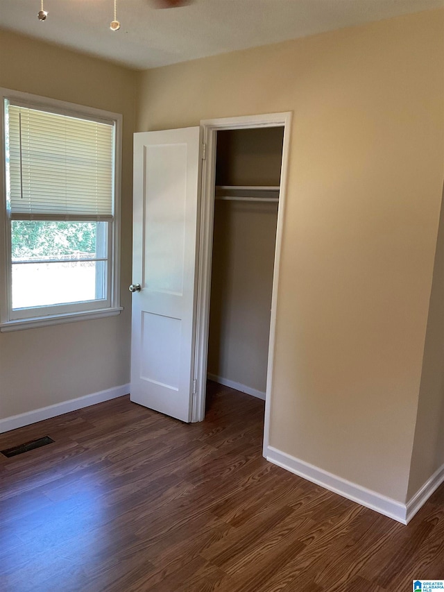 unfurnished bedroom with a closet and dark hardwood / wood-style flooring