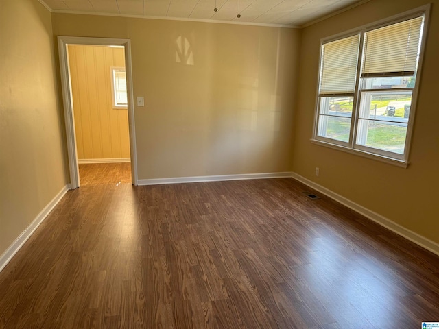 spare room with ornamental molding and dark wood-type flooring