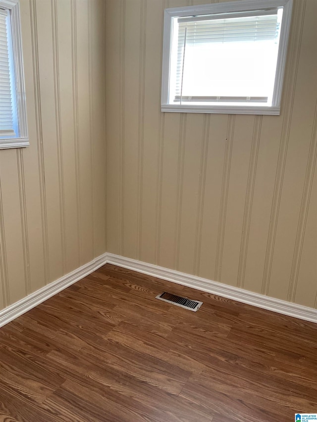 empty room featuring dark hardwood / wood-style flooring and a wealth of natural light