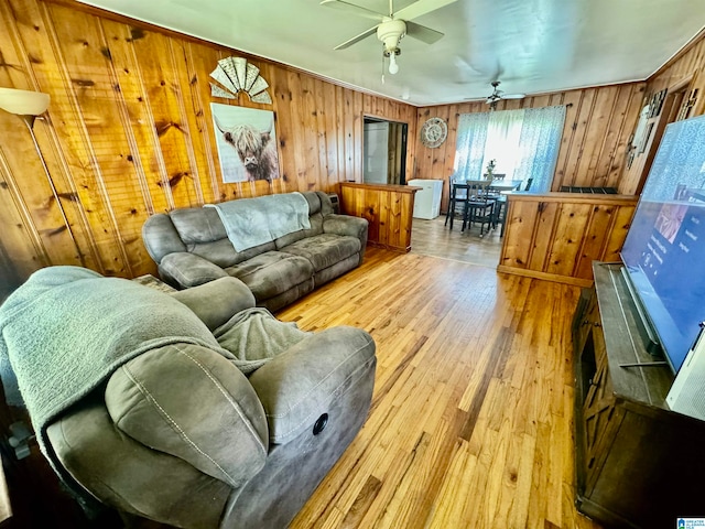 living room featuring light hardwood / wood-style floors, wooden walls, and ceiling fan