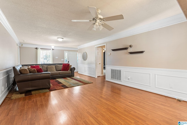 living room with ornamental molding, hardwood / wood-style flooring, ceiling fan, and a textured ceiling