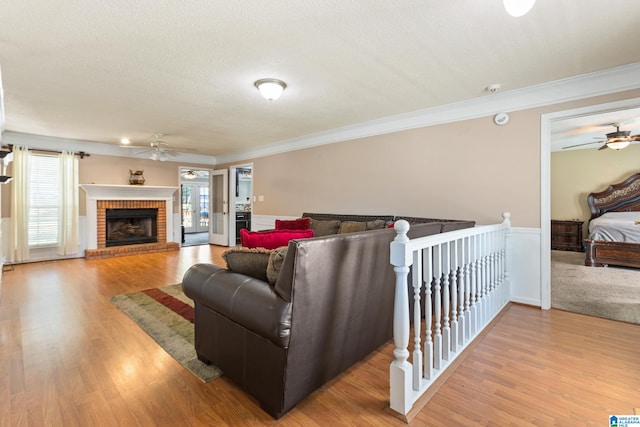 living room with a textured ceiling, light wood-type flooring, and ornamental molding