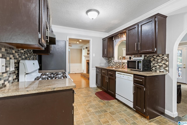 kitchen with white appliances, crown molding, dark brown cabinetry, sink, and backsplash